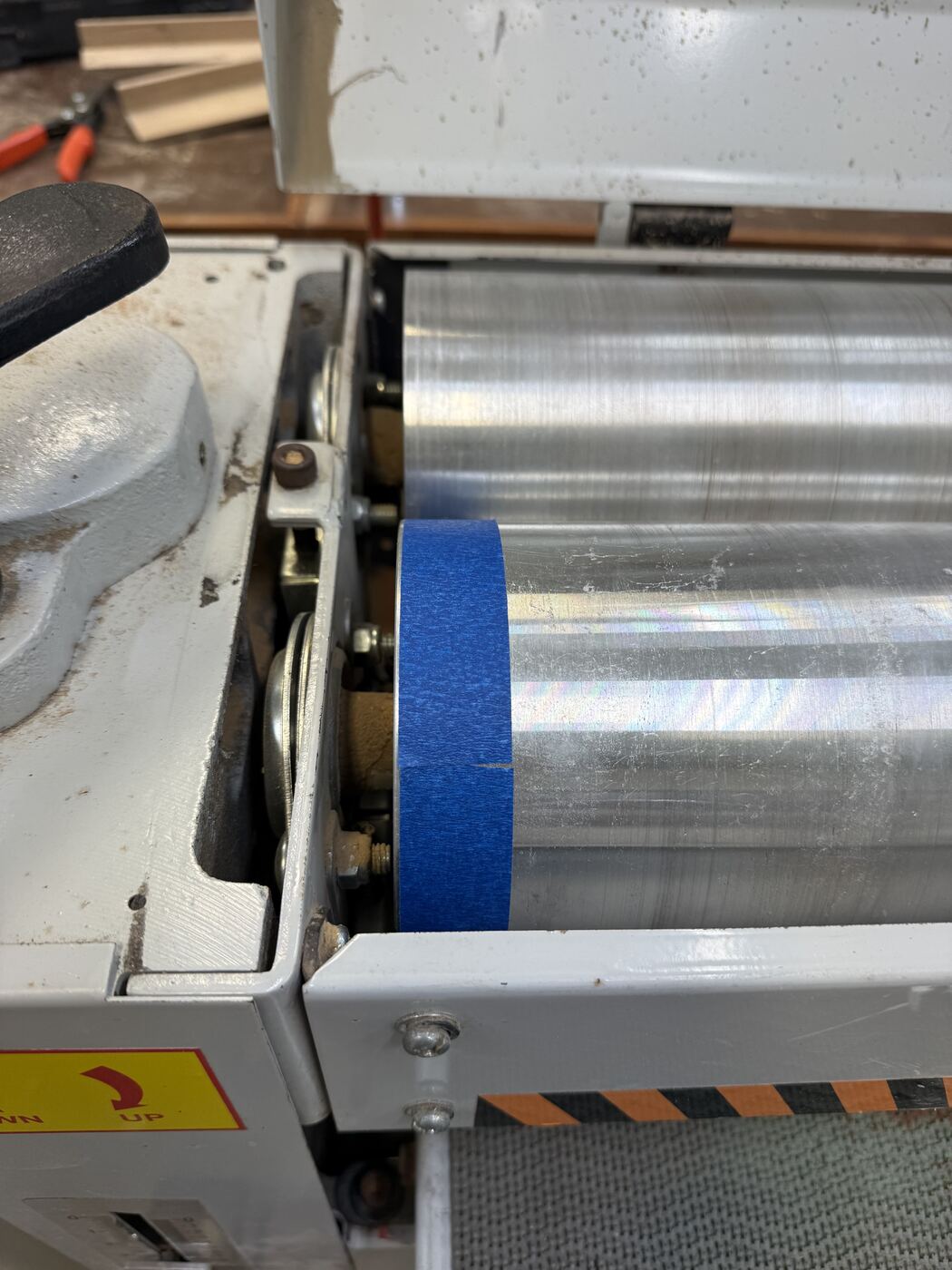 Blue painter's tape wrapped once around the sanding drum, marking where the wrap meets itself.