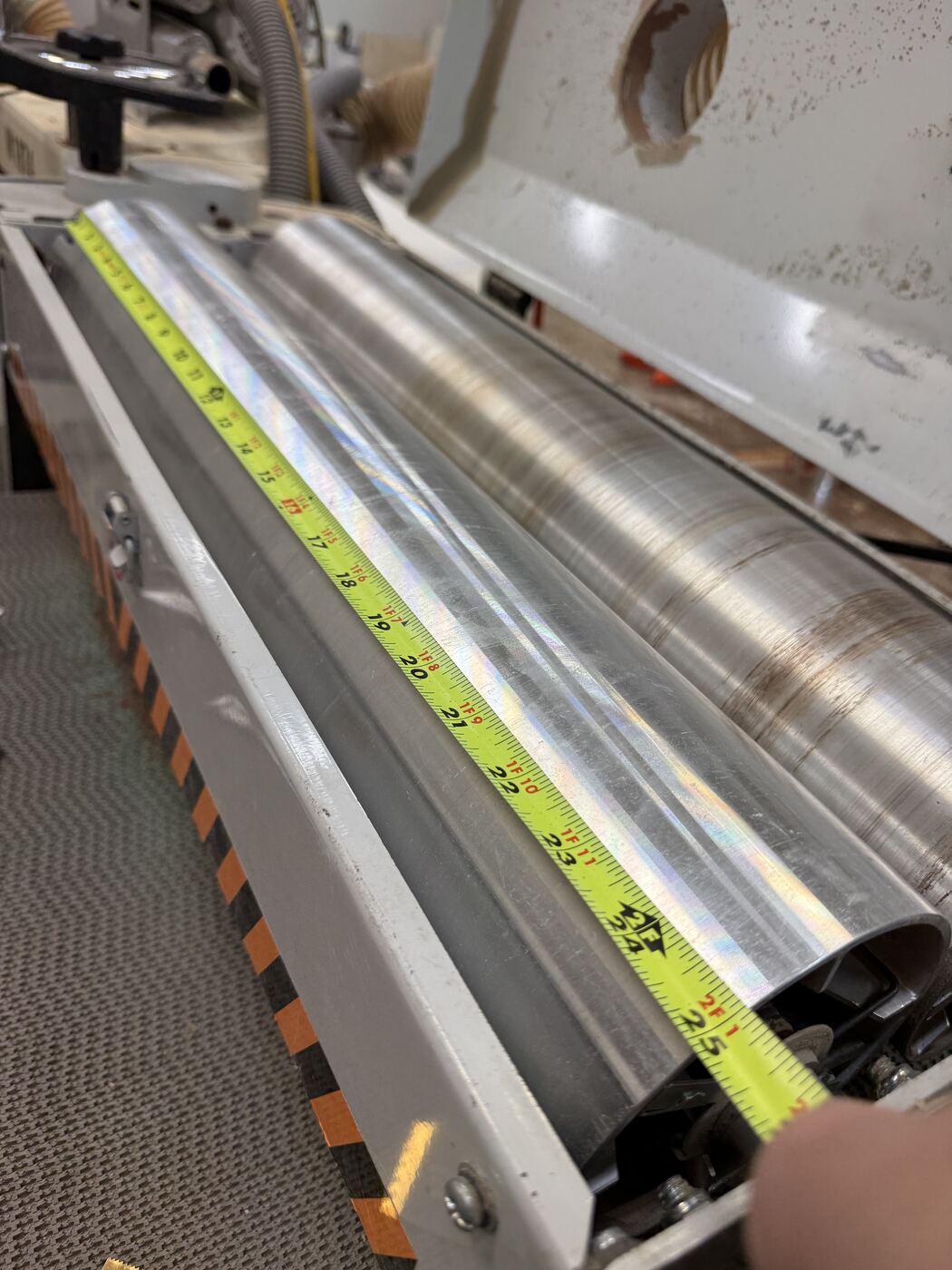 Tape measure run along the sanding drum's roller, reading in the low twenties of inches.