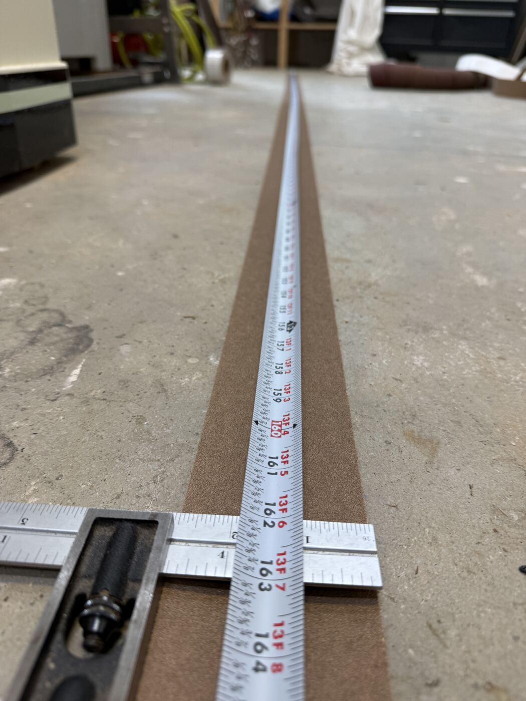 Tape measure laid out along the full length of the sandpaper strip on the floor.